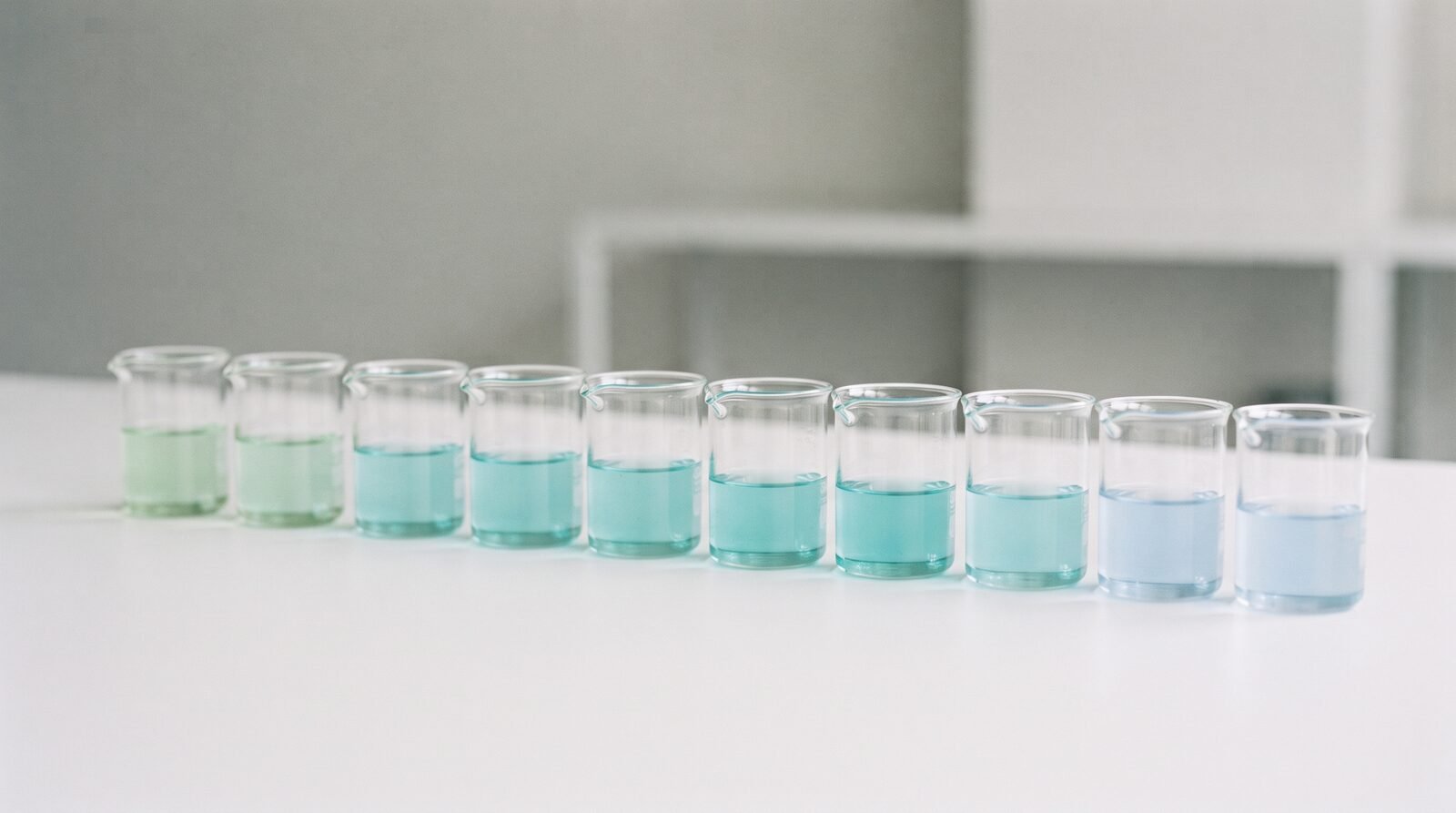 A row of water samples in glass beakers showing subtle differences